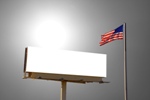 A roadside billboard with an American Flag next to it. The sun was behind the billboard and to the left